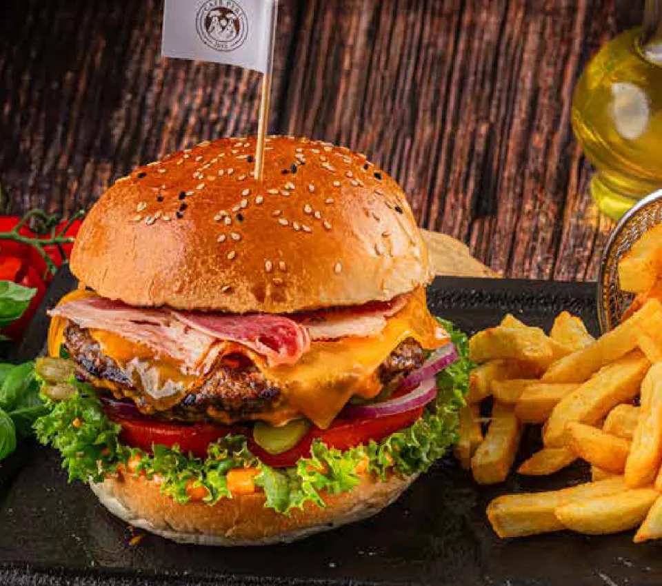 Peri Burger im Café Peri Berlin: 160 g Rinderhack mit Pastırma, Cheddar, Salat, Tomate und Gewürzgurke im Sesambrötchen, dazu Pommes im Körbchen.