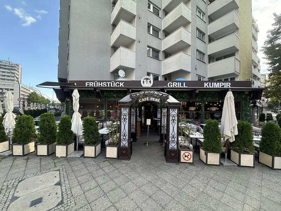Außenansicht des Café Peri an der Potsdamer Straße 203 in Berlin-Schöneberg mit der Markise „Frühstück · Grill · Kumpir“ und der Terrasse davor.