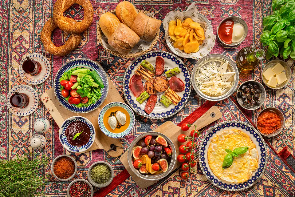 Serpme Kahvaltı im Café Peri Berlin: Käsesorten, Oliven, Honig mit Kaymak, Marmeladen, frisches Gemüse, Simit und Çay auf einem großen Tisch.